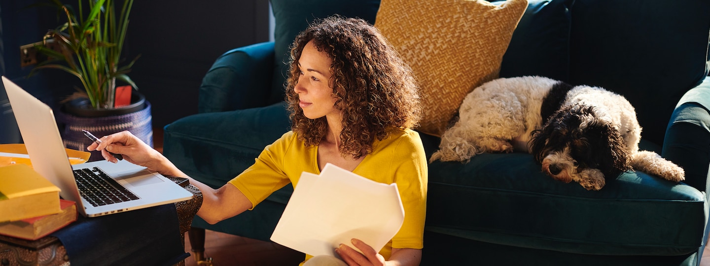 Woman looking at laptop with dog by her side
