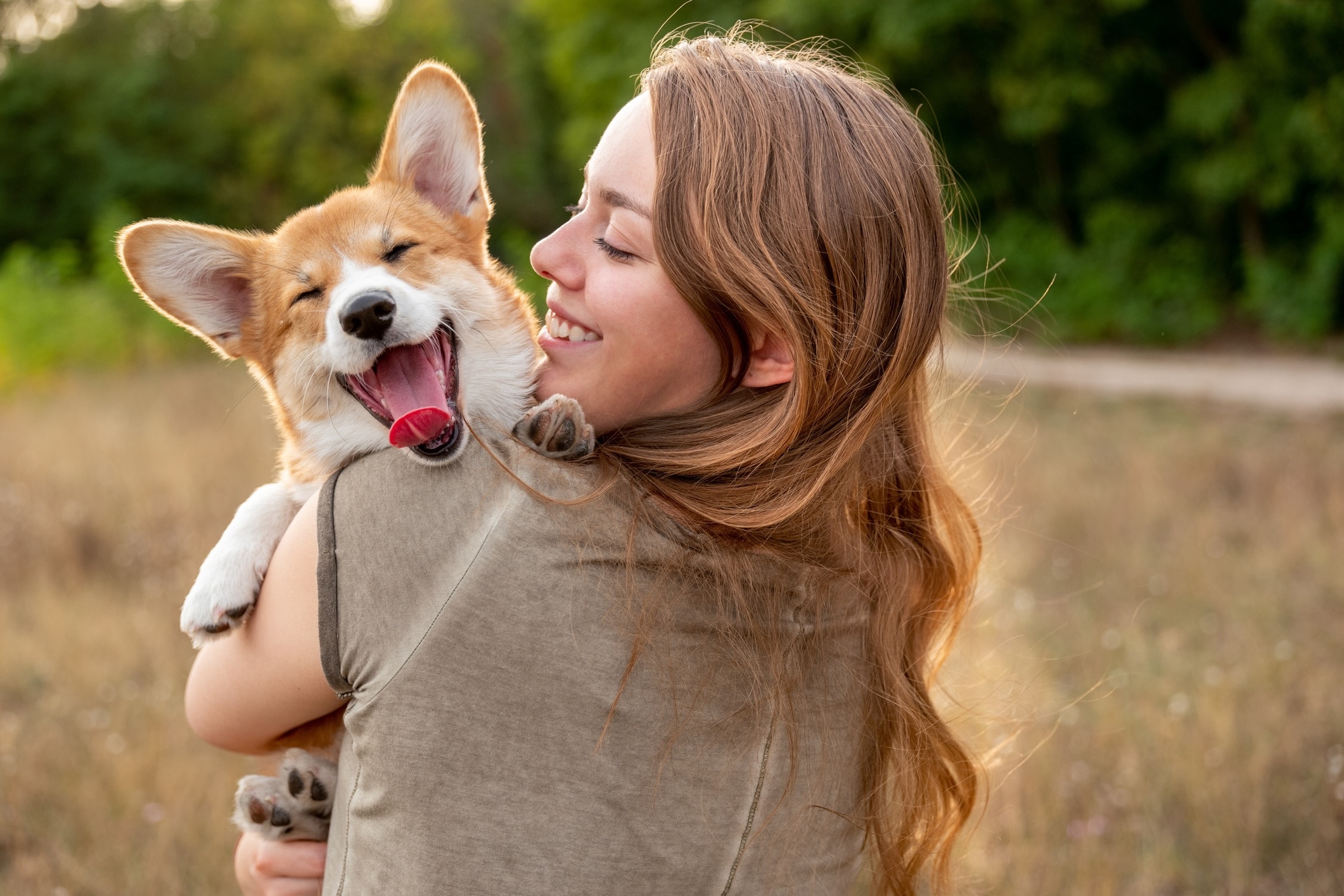 woman holding a white and tan corgi who is smiling