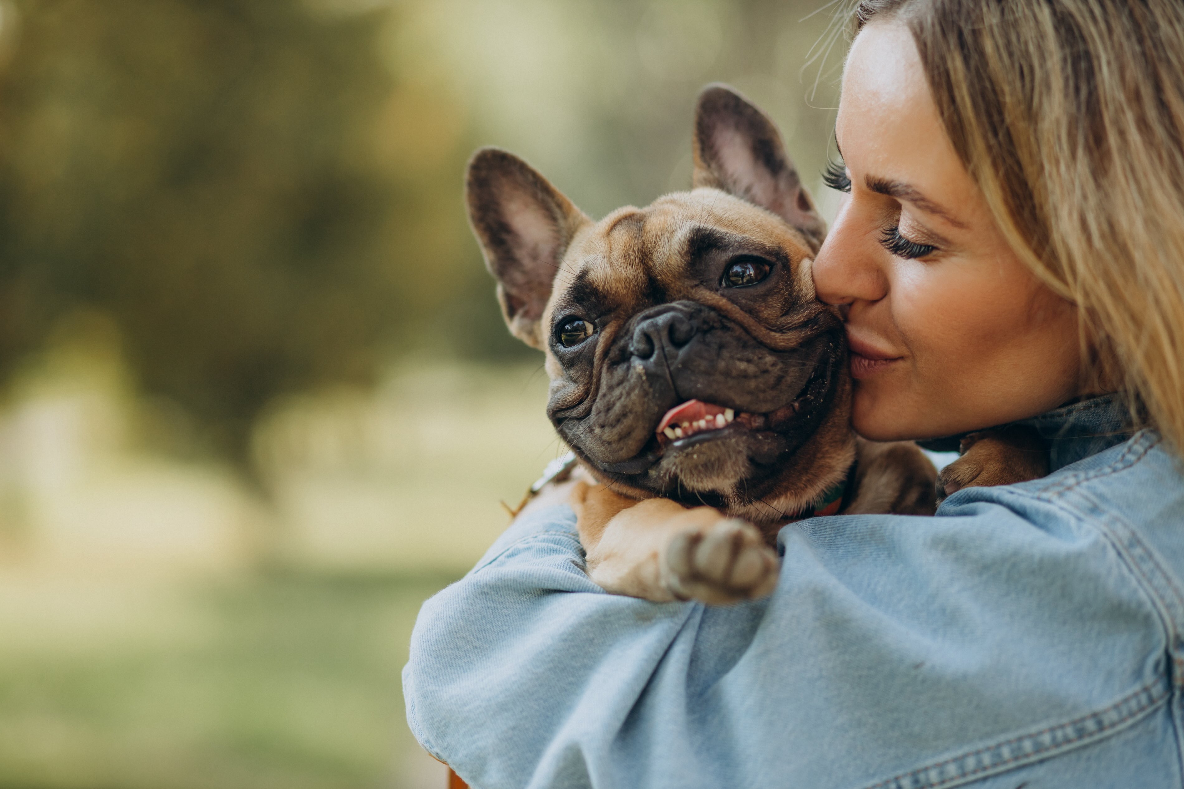 woman holding and hugging a brown french bulldog