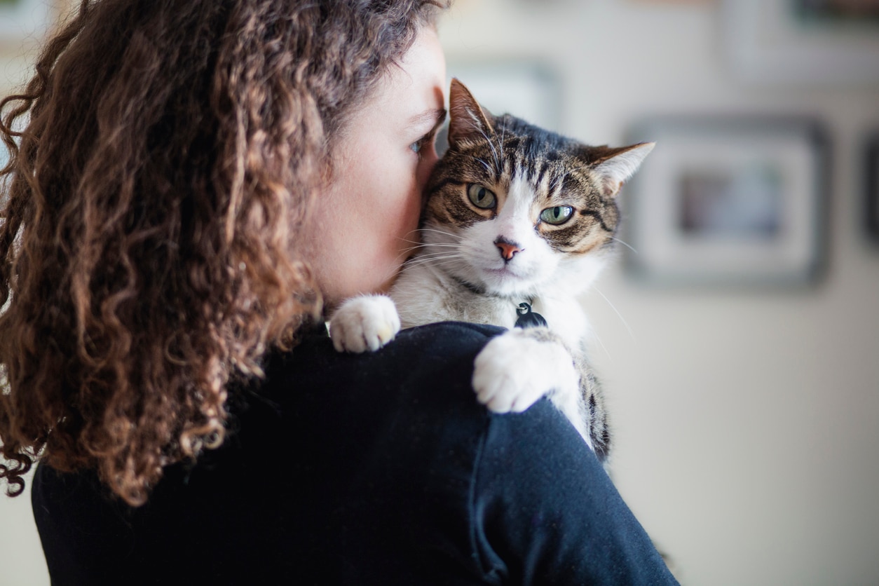 woman holding a white and brown tabby cat