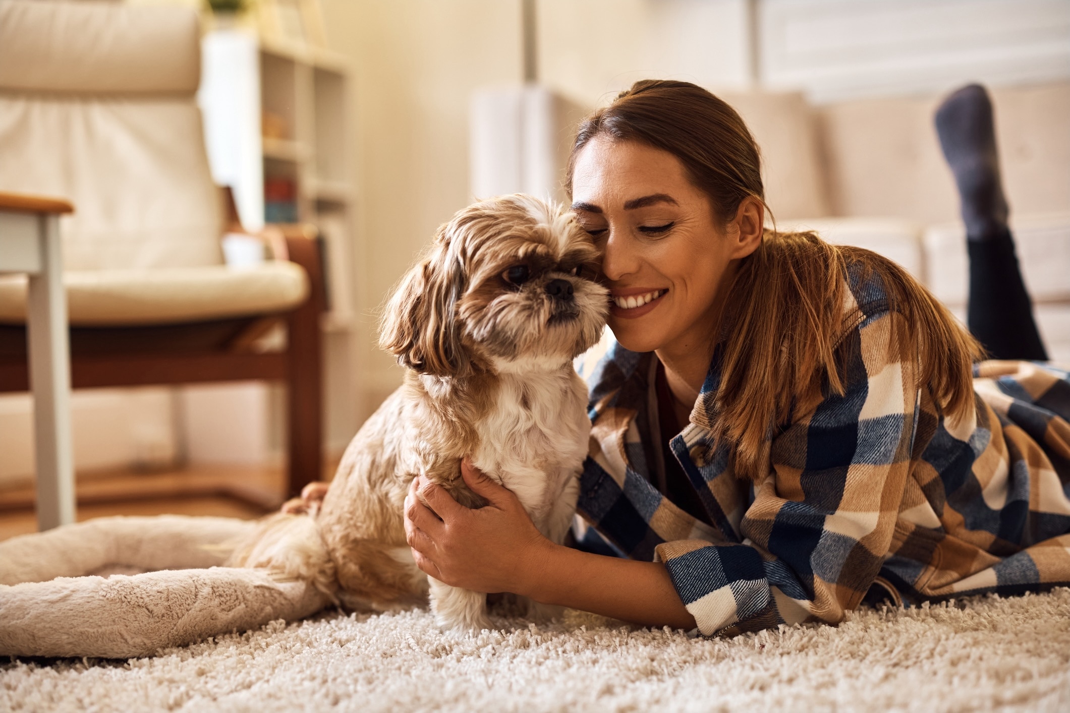 woman lying in the ground of a bedroom and hugging a shih tzu