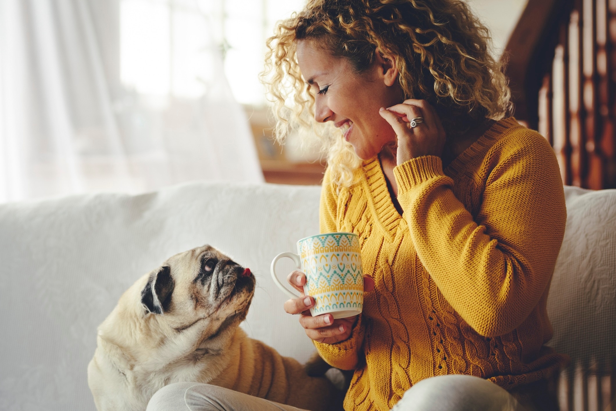 pug and woman sitting on the couch and looking at each other