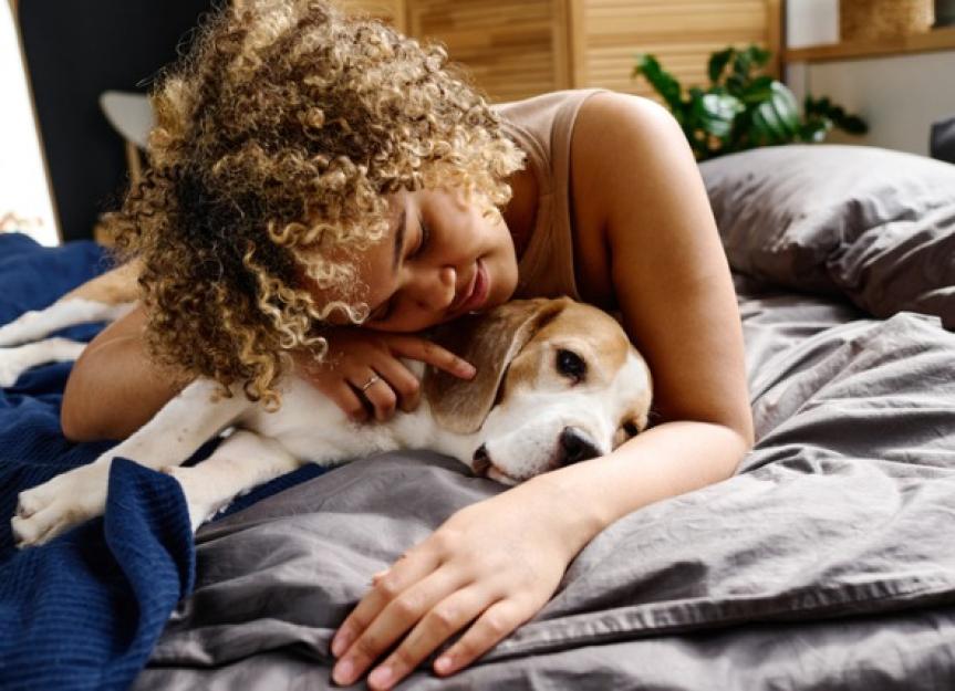 https://image.petmd.com/files/styles/863x625/public/2022-10/woman-cuddling-with-dogs-on-bed-picture-id1394774841.jpg