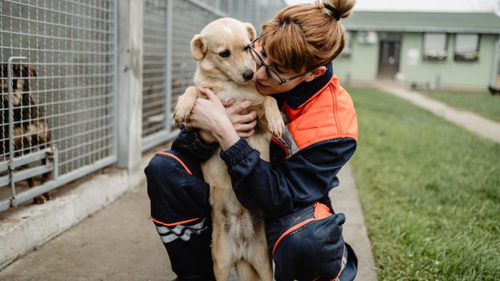 woman holding dog outside shelter