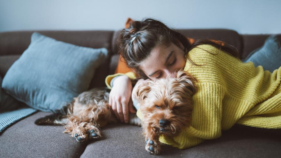 woman-hugging-dog-on-couch