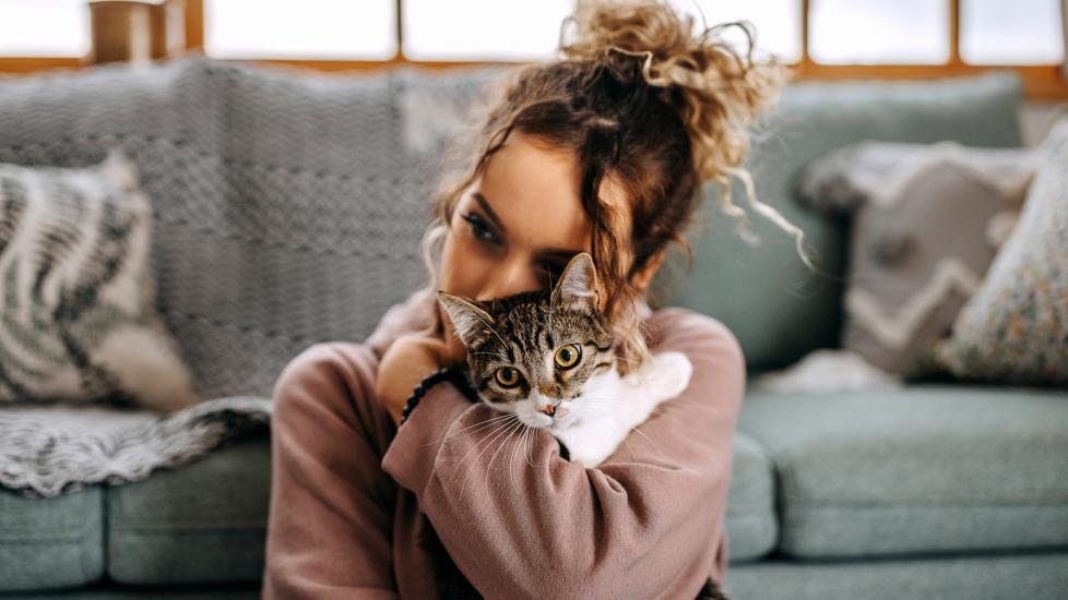woman cuddling cat in front of couch