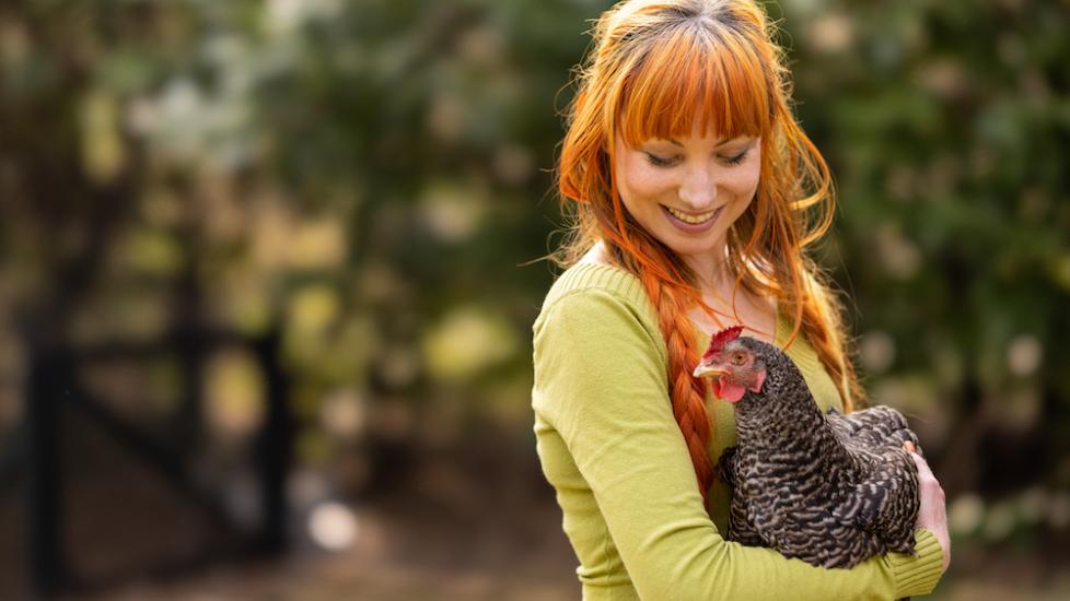 Red-haired woman holding chicken