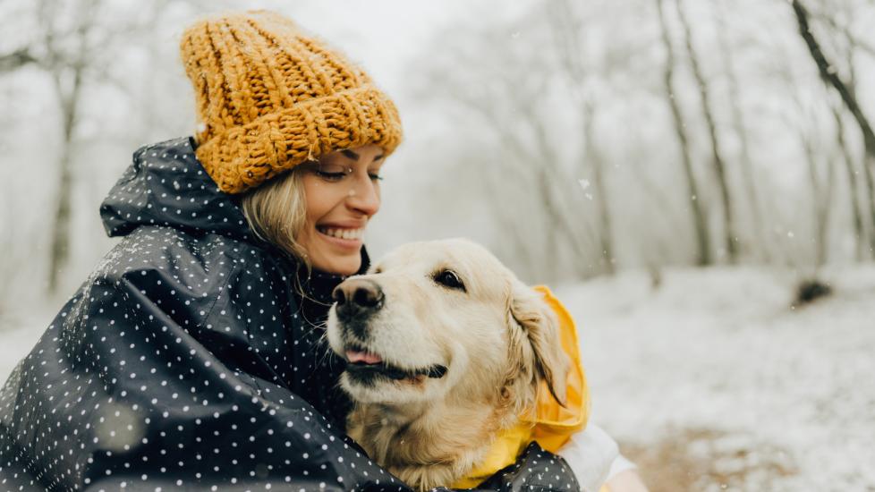 A pet parent and their dog enjoy a snowy day.