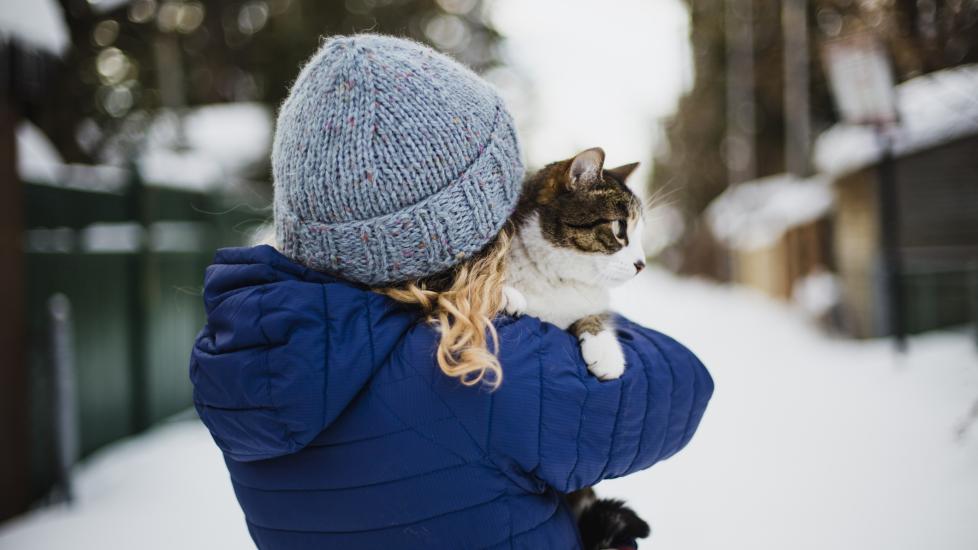 A pet parent holds her cat on a cold day.