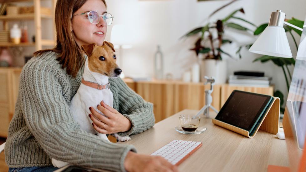 A pet parent sits with her dog during an online vet appointment.