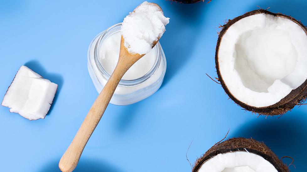 coconut oil for cats: coconut oil in jar with spatula against blue background