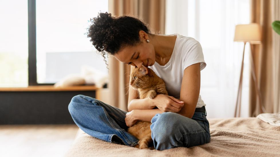 a woman cuddles her cat while sitting on couch.